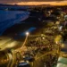 Veduta aerea al tramonto del lungomare di Marina di Ragusa affollato durante Marina Gourmet, tra luci e bancarelle
