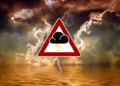 Cielo di tempesta su mare con fulmine e simbolo triangolare di allerta meteo con nuvola e lampo