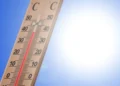 Termometro da esterno con colonnina di mercurio rossa che supera i 40 gradi sotto un cielo azzurro e sole intenso
