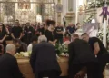 Portatori sollevano il feretro di Michela Canto nella Basilica di Ispica, accanto al suo ritratto tra fiori bianchi