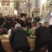 Portatori sollevano il feretro di Michela Canto nella Basilica di Ispica, accanto al suo ritratto tra fiori bianchi