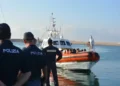 Agenti di Polizia in banchina davanti a una motovedetta della Guardia costiera con migranti a bordo, porto di Pozzallo