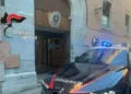 Auto dei carabinieri con i lampeggianti accesi davanti all'ingresso di una caserma dell'Arma, con lo stemma sopra la porta