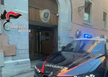 Auto dei carabinieri con i lampeggianti accesi davanti all'ingresso di una caserma dell'Arma, con lo stemma sopra la porta