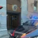 Auto dei carabinieri con i lampeggianti accesi davanti all'ingresso di una caserma dell'Arma, con lo stemma sopra la porta