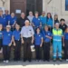 Volontari della Misericordia di Modica in polo blu davanti all'ingresso della sede, con un sacerdote al centro