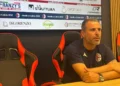 Filippo Raciti, allenatore del Modica, seduto in sala stampa con le braccia sul tavolo, davanti al pannello degli sponsor