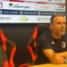 Filippo Raciti, allenatore del Modica, seduto in sala stampa con le braccia sul tavolo, davanti al pannello degli sponsor