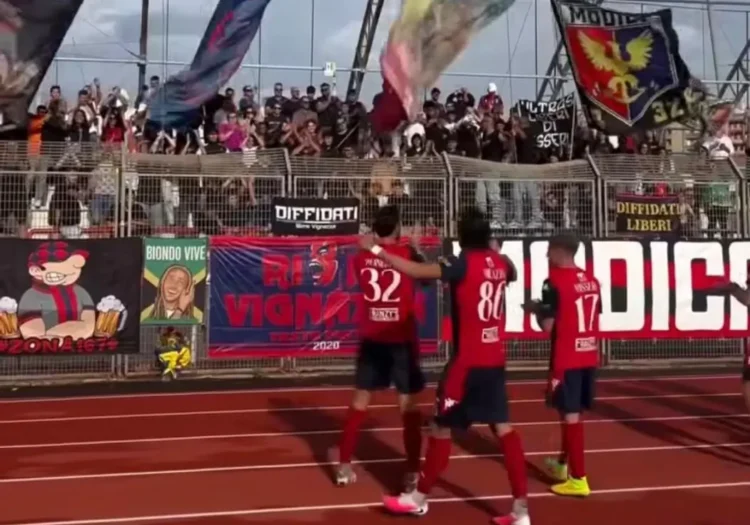 Giocatori del Modica in maglia rossa salutano i tifosi sugli spalti dopo la gara con il Favara Castrum, tra striscioni
