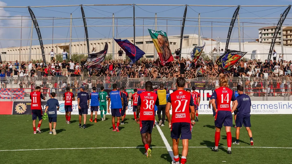 Giocatori del Modica in campo al Pietro Scollo, tifosi con bandiere sugli spalti prima della gara di Serie D
