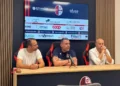 Tavolo della conferenza stampa del Modica Calcio, con logo del club e sponsor sullo schermo alle spalle di tre uomini seduti
