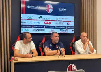 Tavolo della conferenza stampa del Modica Calcio, con logo del club e sponsor sullo schermo alle spalle di tre uomini seduti