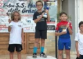 Un giovane ciclista della Motyka Bike School alza il trofeo al centro del podio, tra altri due atleti