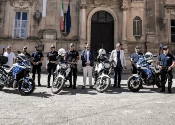 Agenti della Polizia Locale con le motociclette del Nucleo Motociclisti davanti a un edificio storico di Ragusa