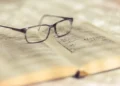 Occhiali da vista appoggiati su un libro antico aperto, con pagine ingiallite e annotazioni scritte a mano
