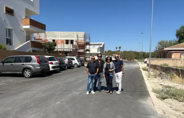 Amministratori comunali su una strada asfaltata di recente a Comiso, con auto parcheggiate sullo sfondo