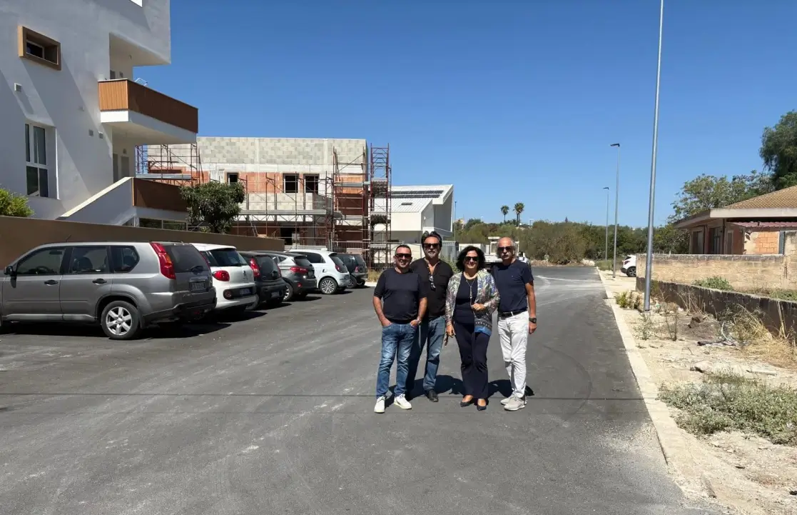 Amministratori comunali su una strada asfaltata di recente a Comiso, con auto parcheggiate sullo sfondo