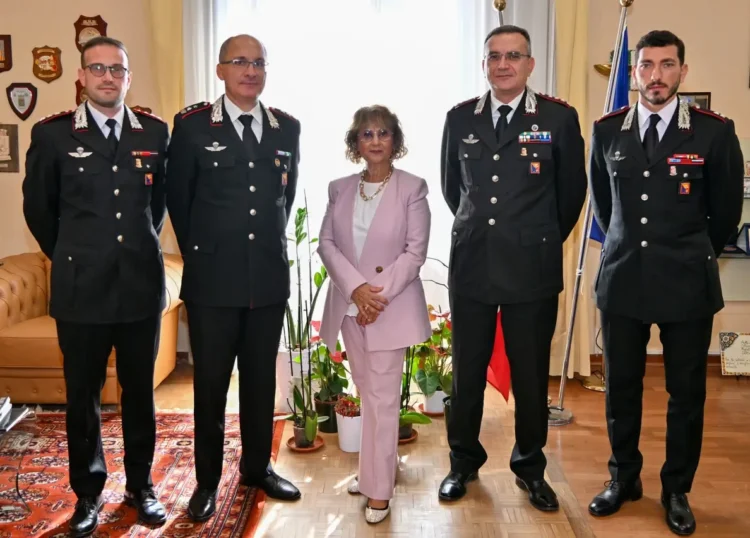 Il Prefetto di Ragusa con quattro ufficiali dei Carabinieri in uniforme, in un ufficio con bandiere e stemmi