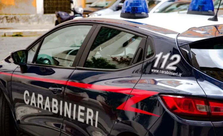 Auto dei Carabinieri con lampeggianti blu e scritta 112, ripresa di lato mentre è parcheggiata in una via cittadina