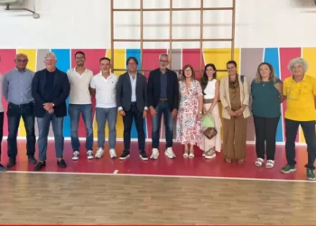Gruppo di persone in posa nella palestra rinnovata di San Giacomo, frazione di Ragusa, tra pareti colorate