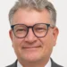 Ritratto di Paolo Ferrara, vicecommissario provinciale del Movimento per l'Autonomia, con occhiali e giacca grigia