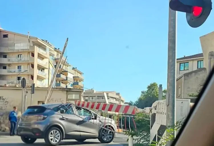 Sbarra del passaggio a livello di via Paestum a Ragusa appoggiata su un'auto grigia, con il semaforo rosso acceso