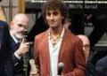 Davide Simone Cavallo sul palco con la pergamena da poliziotto ad honorem, tra due uomini che parlano al microfono