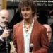 Davide Simone Cavallo sul palco con la pergamena da poliziotto ad honorem, tra due uomini che parlano al microfono