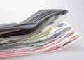 Portafoglio di pelle grigia aperto, con una pila di banconote da euro di vari tagli