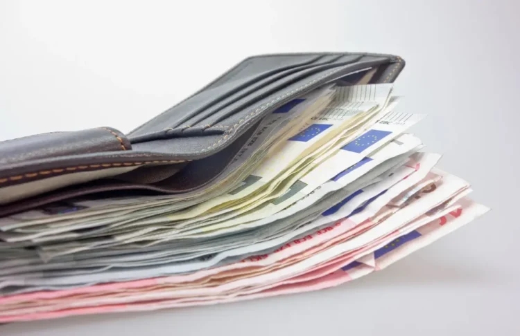 Portafoglio di pelle grigia aperto, con una pila di banconote da euro di vari tagli