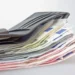 Portafoglio di pelle grigia aperto, con una pila di banconote da euro di vari tagli