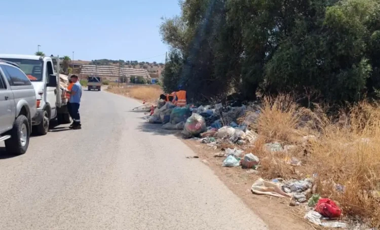 Rifiuti abbandonati sul ciglio di una strada provinciale, operatori al lavoro per la rimozione con un mezzo del Consorzio