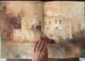 Quaderno di acquerelli aperto: disegno di un edificio in pietra, tenuto da una mano