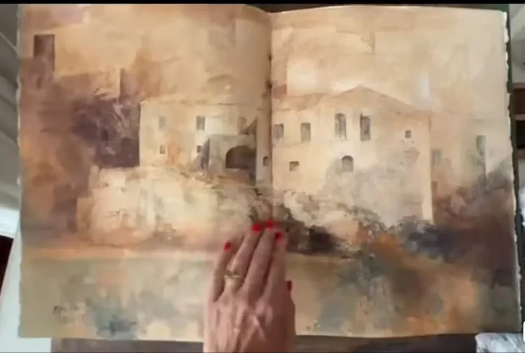 Quaderno di acquerelli aperto: disegno di un edificio in pietra, tenuto da una mano