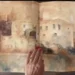 Quaderno di acquerelli aperto: disegno di un edificio in pietra, tenuto da una mano