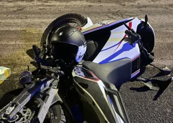 Santa Croce Camerina, moto bianca e nera a terra sull'asfalto di notte con il casco appoggiato sul serbatoio