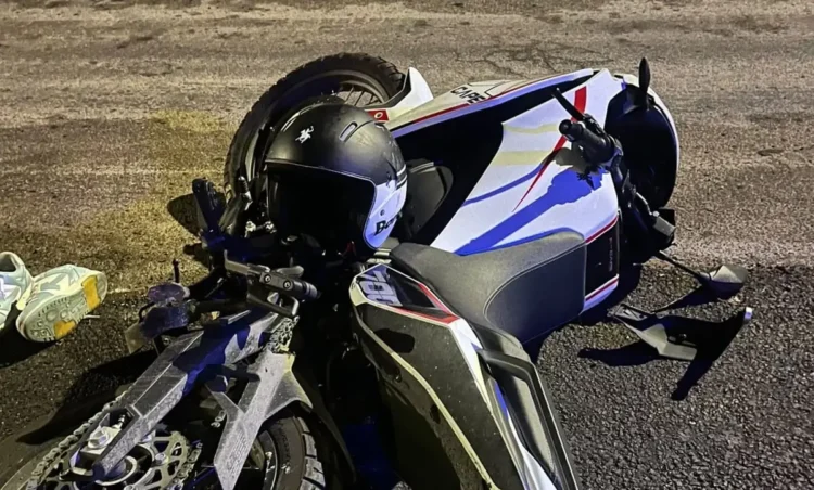 Santa Croce Camerina, moto bianca e nera a terra sull'asfalto di notte con il casco appoggiato sul serbatoio