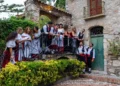Gruppo folk in costume tradizionale siciliano su una scala di un antico edificio in pietra, per la sagra della vendemmia