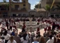 Gruppo folk in costume rosso e bianco balla attorno alla fontana della piazza di Pedalino durante la sagra della vendemmia