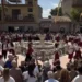 Gruppo folk in costume rosso e bianco balla attorno alla fontana della piazza di Pedalino durante la sagra della vendemmia