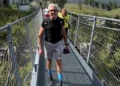 Salvatore Cavallaro cammina su un ponte sospeso in un bosco durante un'escursione in montagna