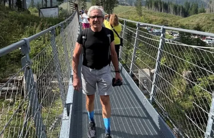 Salvatore Cavallaro cammina su un ponte sospeso in un bosco durante un'escursione in montagna