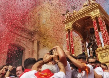 Il simulacro di San Giovanni Battista tra i fedeli, sommerso da coriandoli rossi e dorati davanti alla chiesa