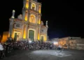 Chiesa di San Giovanni Battista illuminata a Monterosso Almo, pubblico e artista di strada con la ruota durante l'ArtFest