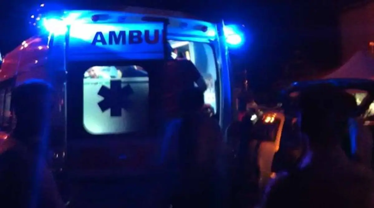 Ambulanza del 118 a porte aperte durante un intervento notturno di soccorso, persone intorno al mezzo