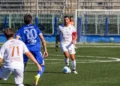 Siracusa-Modica: il capitano in maglia bianca conduce palla a centrocampo, pressato da un avversario in maglia azzurra