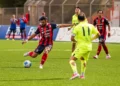Calciatore del Modica in maglia rossoblù con la fascia da capitano calcia il pallone in una gara di Serie D