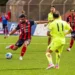 Calciatore del Modica in maglia rossoblù con la fascia da capitano calcia il pallone in una gara di Serie D