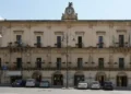 Facciata di Palazzo San Domenico, sede del Comune di Modica, con la torre dell'orologio e le auto parcheggiate davanti