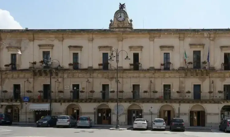 Facciata di Palazzo San Domenico, sede del Comune di Modica, con la torre dell'orologio e le auto parcheggiate davanti